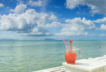 Red cocktail on white table set over ocean