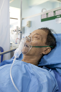 old man wearing oxygen mask asleep on patient bed