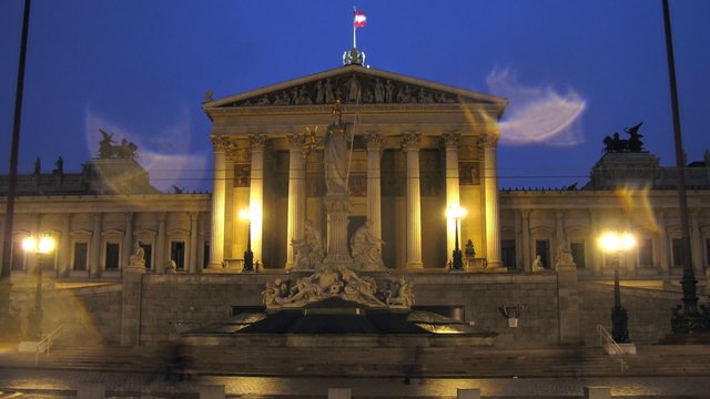 Tourists walk near Austrian parliament in evening