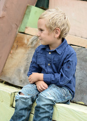 Kind sitzt auf Holzhaus