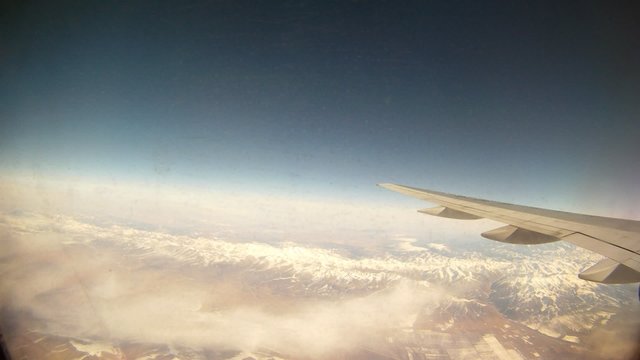 Plane flies by over mountains which are visible from window
