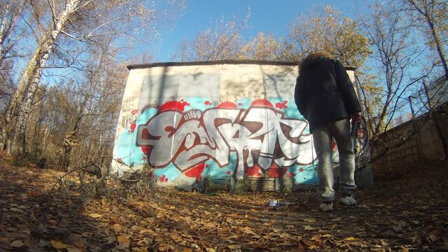 Teenager draw graffiti on wall in autumn on Losinyj island