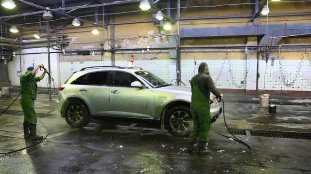 workers of car washing water car with streams of water from
