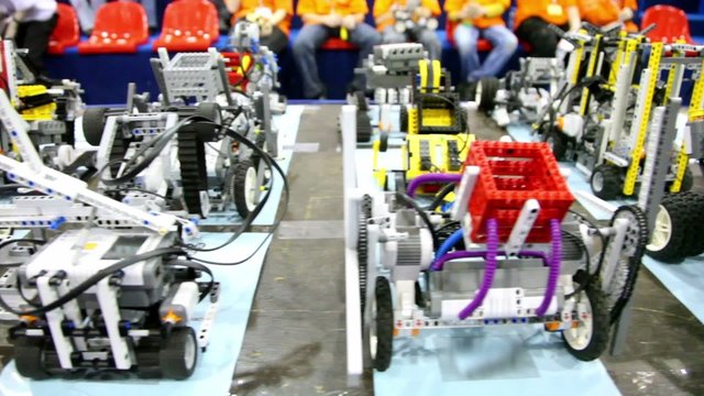 Many different oy robots stand on table at background of many