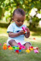 Little african american baby boy playing in the grass