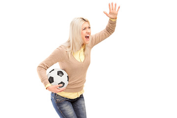 A female sport fan holding a football and shouting