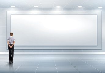 Fototapeta premium Business person standing near a blank billboard