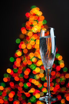 champagne glass against christmas tree bokeh