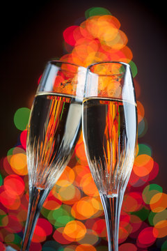 champagne glasses against christmas tree bokeh lights