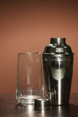 Cocktail shaker and cocktail glass on color background