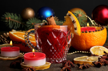 Fragrant mulled wine in glass with spices and oranges around