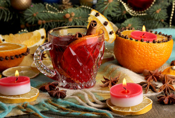 Fragrant mulled wine in glass with spices and oranges around