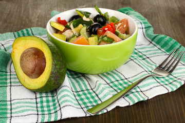 Tasty avocado salad in bowl  on wooden table close-up