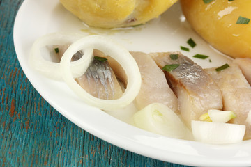 Dish of herring on plate on blue wooden table close-up