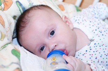 The baby eats from a small bottle (3 months)
