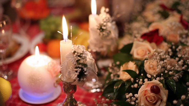 In twilight on festive table there are candles, bouquets,