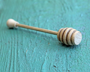 Wooden honey drizzler on wooden background, close-up