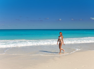 Fototapeta na wymiar Młoda kobieta idzie na wybrzeżu oceanu