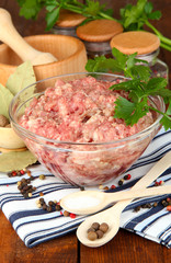 Bowl of raw ground meat with spices on wooden table