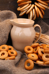 jar of milk, tasty bagels and spikelets on wooden background