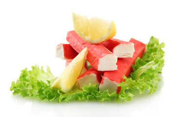 Crab sticks on lettuce leaves with lemon, isolated on white