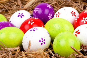 bemalte bunte Eier für Ostern versteckt im Nest aus Stroh