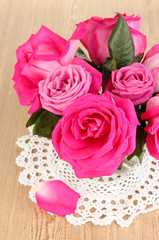 Beautiful pink roses in vase on wooden table close-up