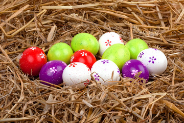 bemalte bunte Eier für Ostern versteckt im Nest aus Stroh