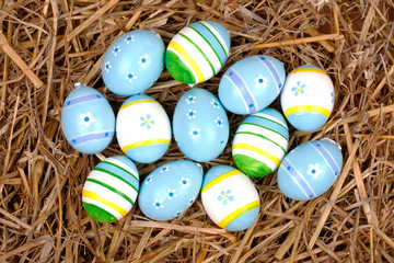 bemalte bunte Eier für Ostern versteckt im Nest aus Stroh