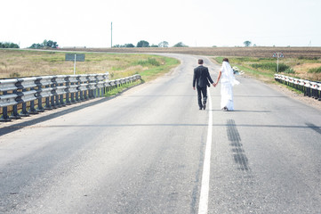 Fototapeta premium newly married couple walking down the road hand in hand