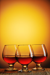 Three glasses of cognac on yellow background