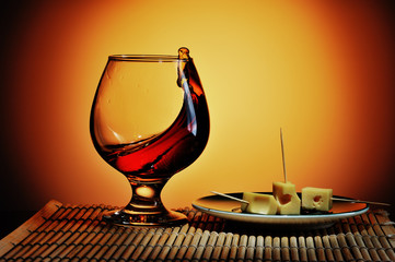 Glass of cognac with cheese plate