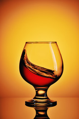 Glass of cognac on yellow background