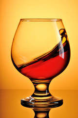 Glass of cognac on yellow background
