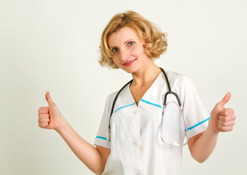 Happy smiling cheerful female doctor with thumbs up gesture