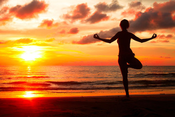 Yoga woman on sea coast in sunset.