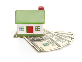 Model of a house lying on some banknotes isolated on white