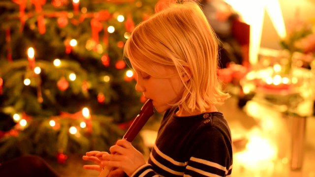 Kleines M&auml;dchen spielt Blockfl&ouml;te vor Christbaum