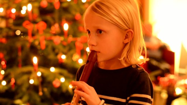 Kleines M&auml;dchen spielt Blockfl&ouml;te vor Christbaum