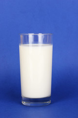Glass of fresh new milk on blue background
