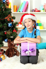Fototapeta na wymiar Little girl holding gift box near christmas tree