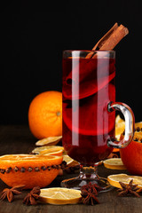Fragrant mulled wine in glass with spices and oranges around