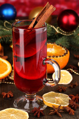 Fragrant mulled wine in glass with spices and oranges around