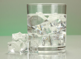 Ice cubes in glass on light green background