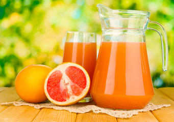 Full glass and jug of grapefruit juice and grapefruits