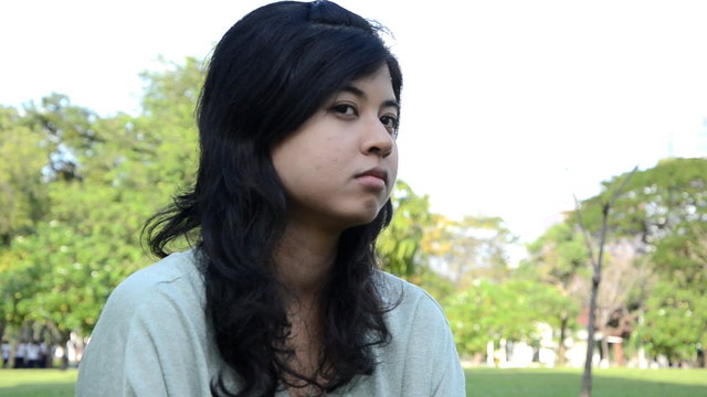 Young, sad, lonely beautiful woman face in the park