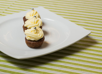 Chocolate cupcakes with silver sprinkles on top on white plate