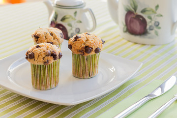 Chocolate chip muffins on white plate and green striped tableclo