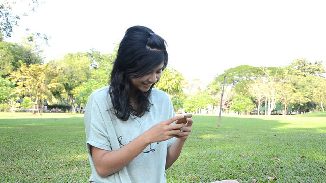 Young woman typing e-mail message on smartphone and laughing