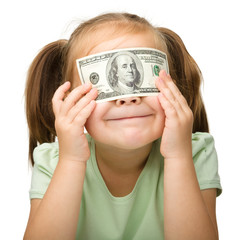 Little girl is covering her eyes with dollars